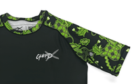 Close-up of GuardX logo on Batik-X Pulse rashguard chest, black fabric with green batik details